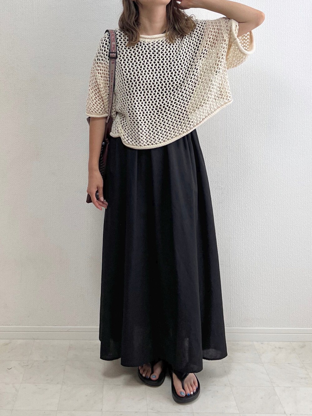 ブラック系のワンピース、ホワイト系のニット/セーター、ブラウン系のショルダーバッグを着用したレディースの夏コーディネートの2枚目の写真