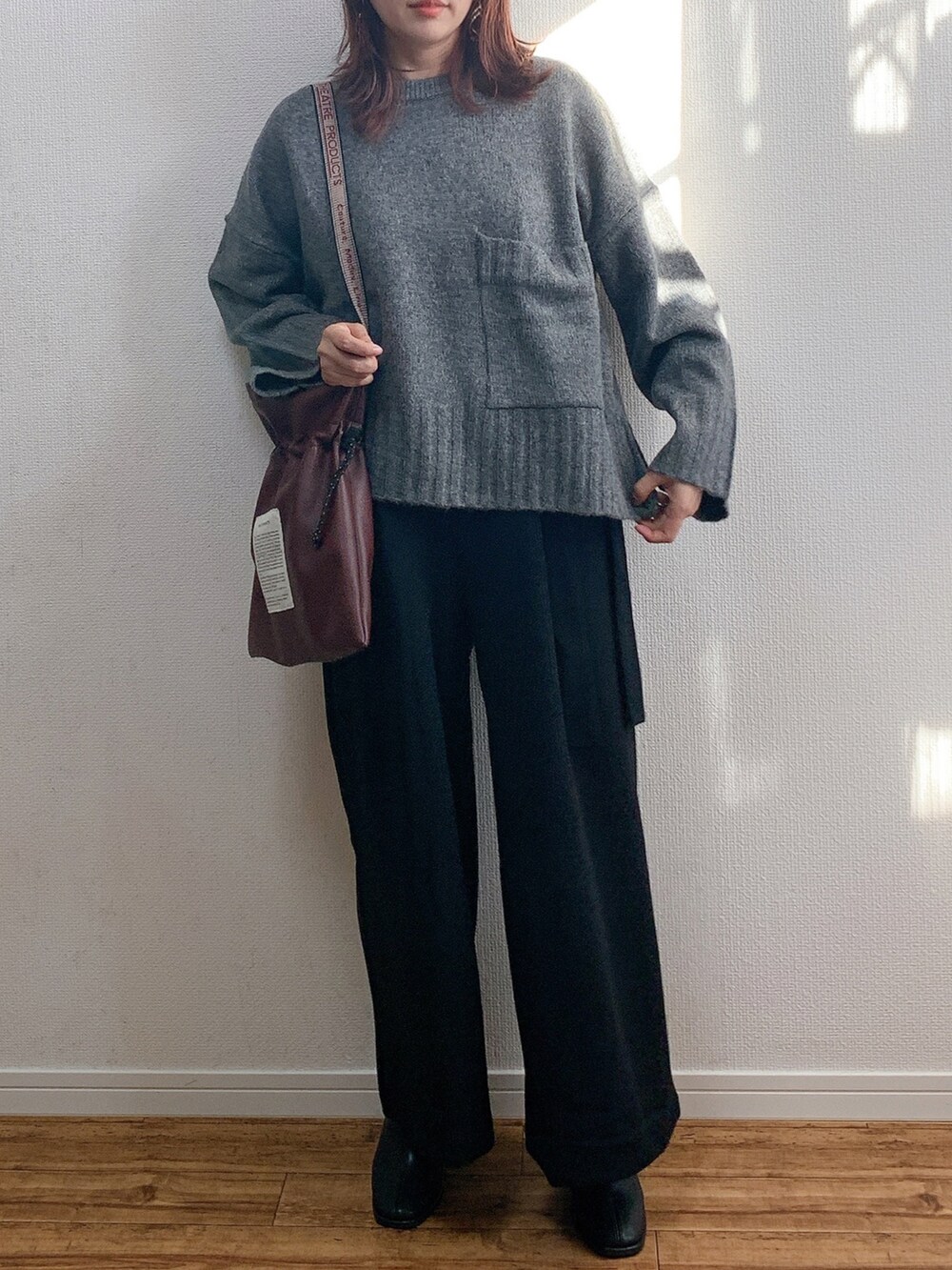 グレー系のニット/セーター、ブラック系のその他パンツ、ブラウン系のショルダーバッグを着用したレディースの秋コーディネートの2枚目の写真