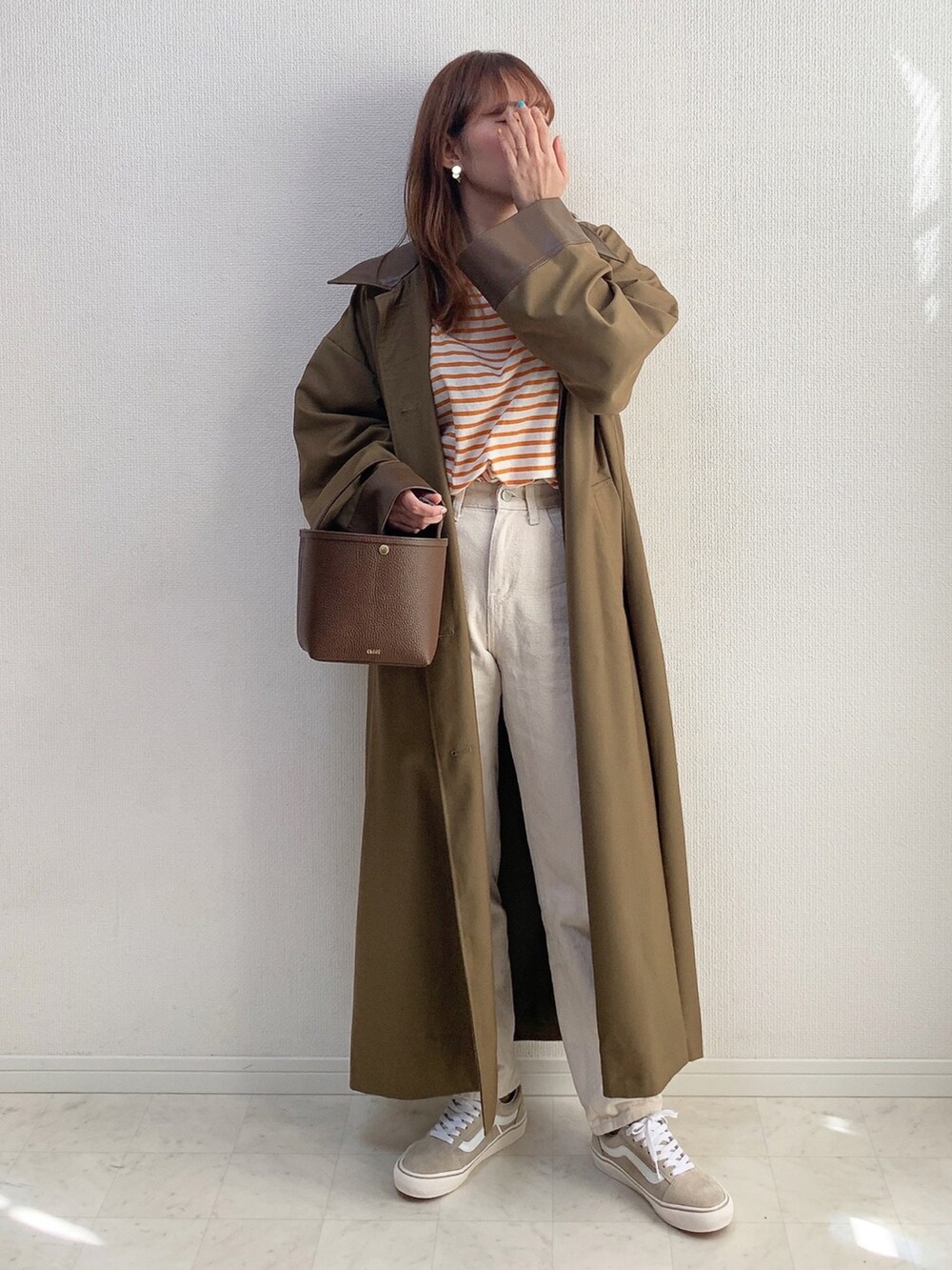 オレンジ系のTシャツ/カットソー、グリーン系のステンカラーコート、ブラウン系のバッグを着用したレディースの冬コーディネートの2枚目の写真