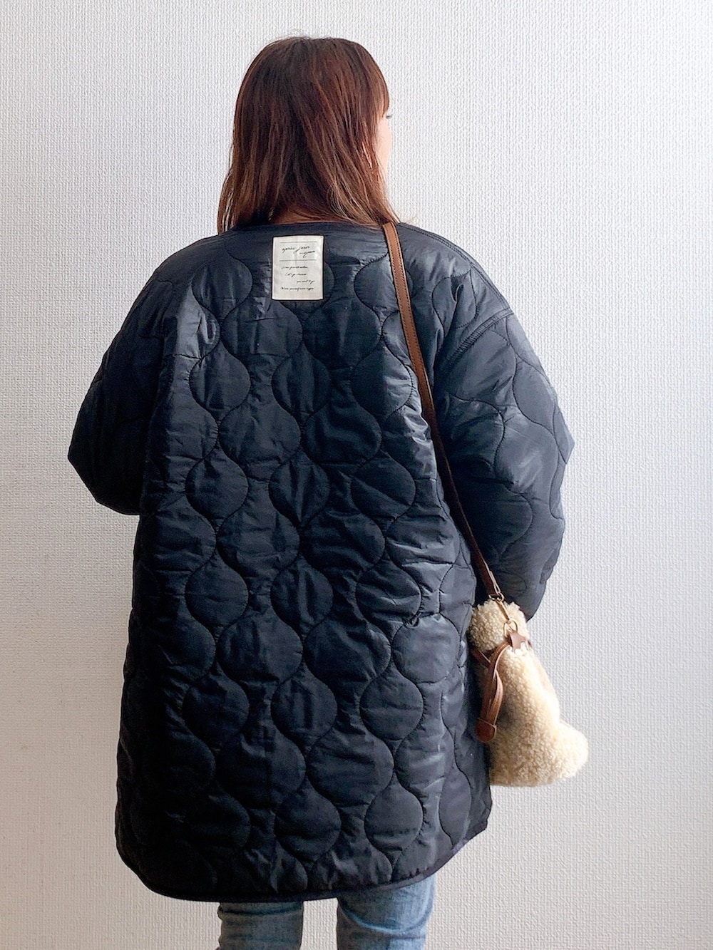 ブラック系のブルゾン、グリーン系のスウェット、ブルー系のデニムパンツを着用したレディースの秋コーディネートの2枚目の写真