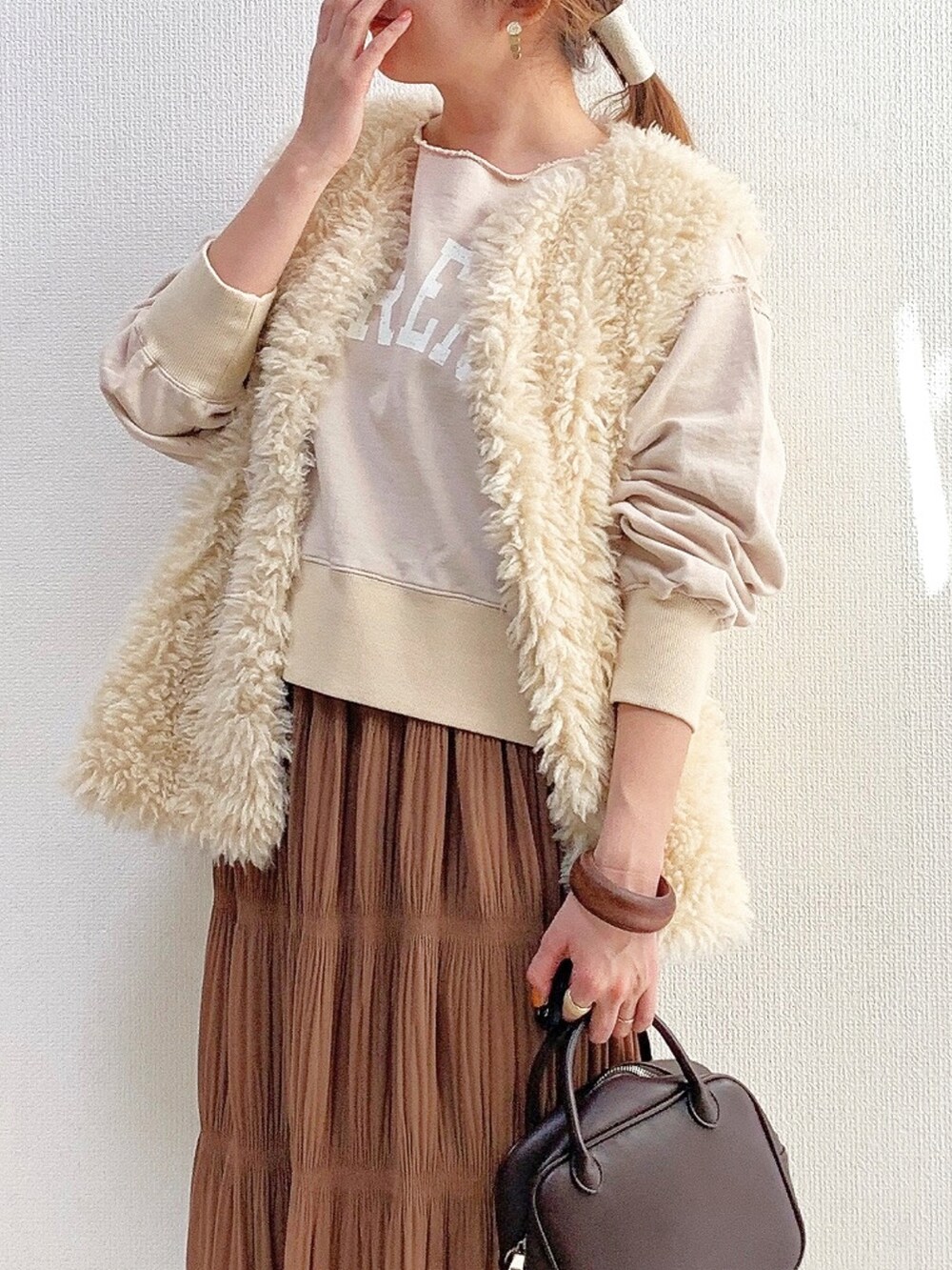 ベージュ系のスウェット、ホワイト系のベスト、イエロー系のスカートを着用したレディースの冬コーディネートの2枚目の写真