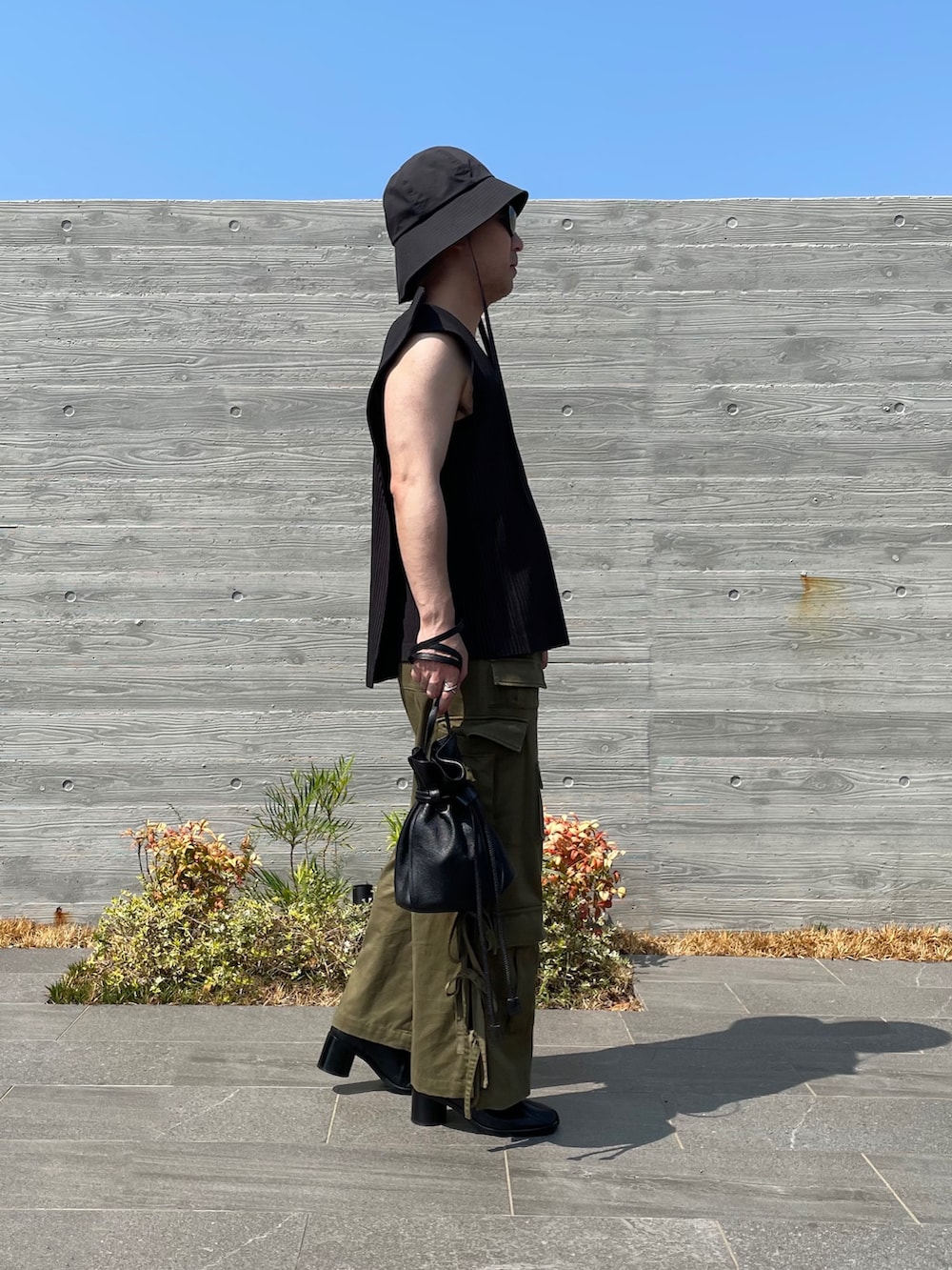 グレー系のベスト、グリーン系のカーゴパンツ、ブラック系のショルダーバッグを着用したメンズの秋コーディネートの2枚目の写真