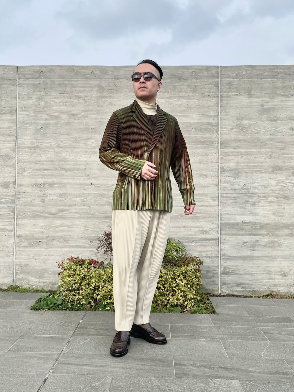 グリーン系のテーラードジャケット、ベージュ系のスラックス、ブラウン系のローファーを着用したメンズの春コーディネートの2枚目の写真