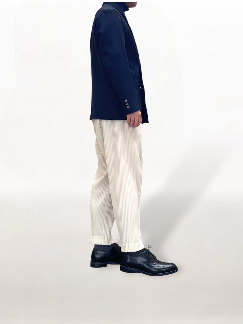 ホワイト系のスラックス、ブルー系のテーラードジャケット、ブラック系のドレスシューズを着用したメンズの冬コーディネートの2枚目の写真