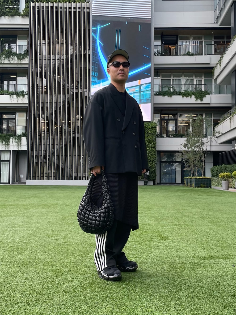 ブラック系のテーラードジャケット、ブラック系のハンドバッグ、ブラック系のその他パンツを着用したメンズの秋コーディネートの2枚目の写真