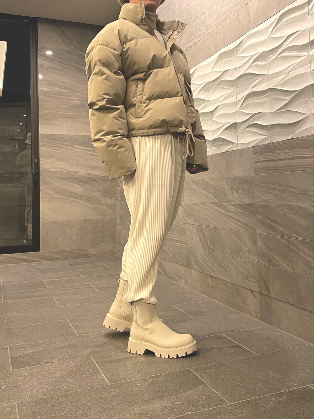 ベージュ系のダウンジャケット/コート、ホワイト系のスラックス、ホワイト系のブーツを着用したメンズの冬コーディネートの2枚目の写真