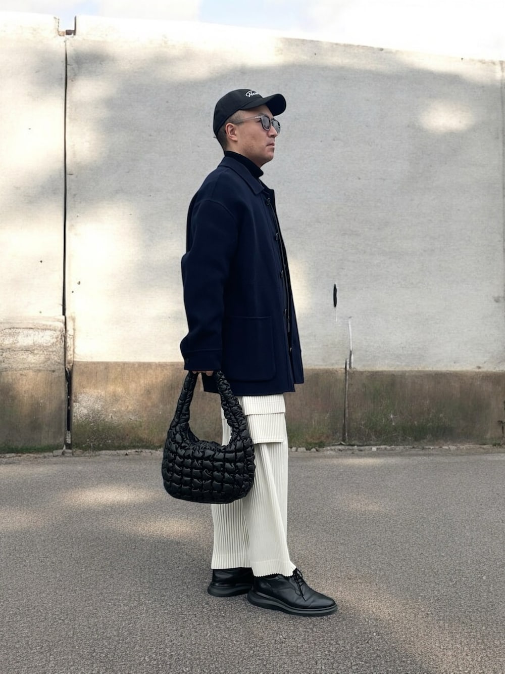 ブルー系のカバーオール、ブラック系のハンドバッグ、ホワイト系のカーゴパンツを着用したメンズの冬コーディネートの2枚目の写真