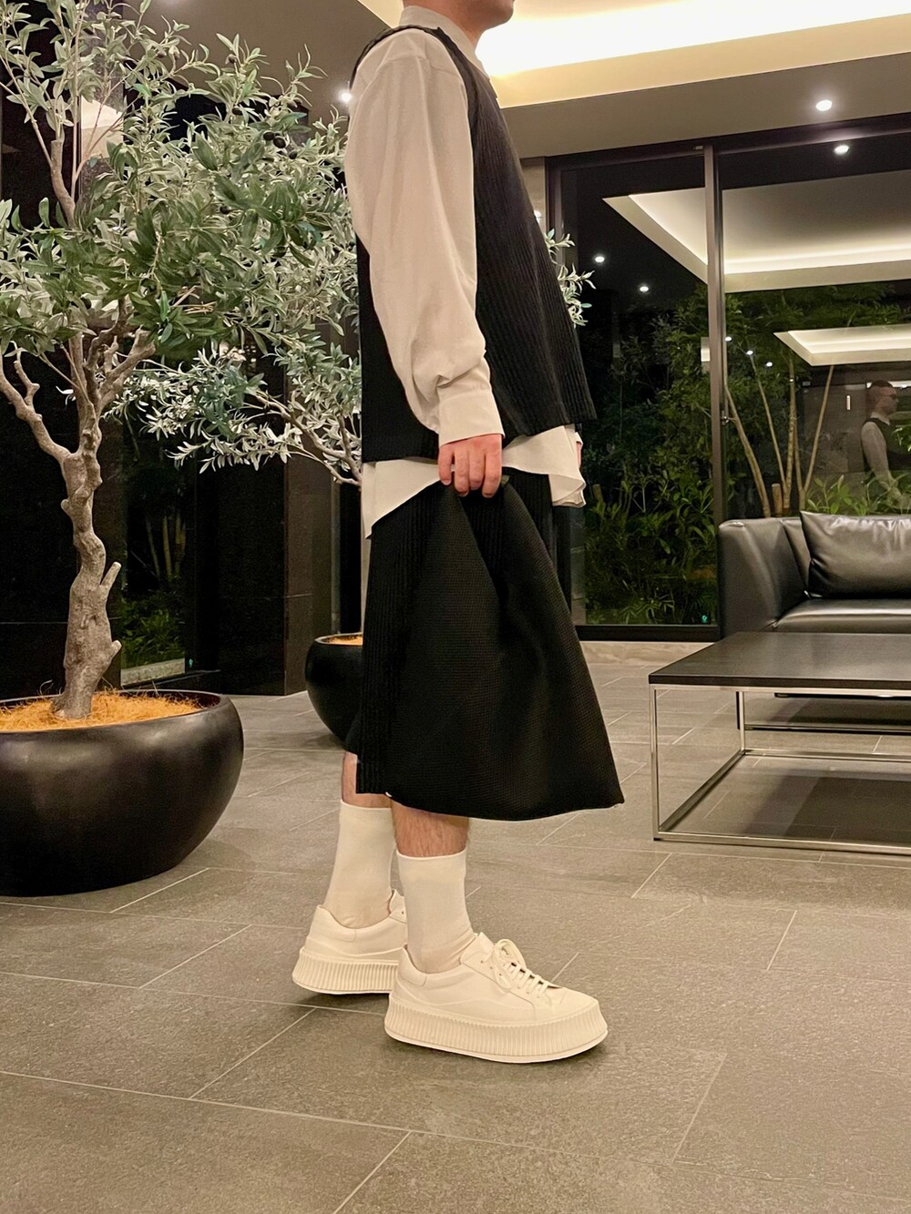 ブラック系のベスト、ブラック系のその他パンツ、ホワイト系のスニーカーを着用したメンズの春コーディネートの3枚目の写真