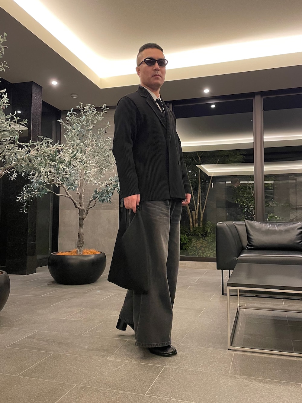 ブラック系のデニムパンツ、ブラック系のトートバッグ、ブラック系のブーツを着用したメンズの春コーディネートの4枚目の写真