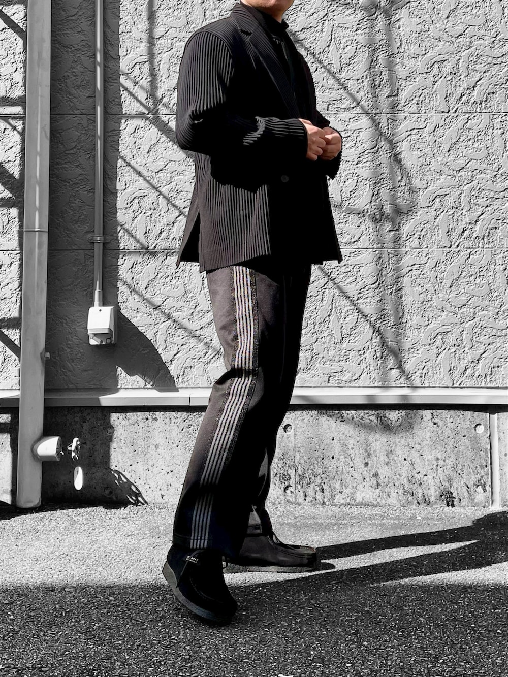 ブラック系のブーツ、ブラック系のベスト、ブラック系のテーラードジャケットを着用したメンズの春コーディネートの2枚目の写真