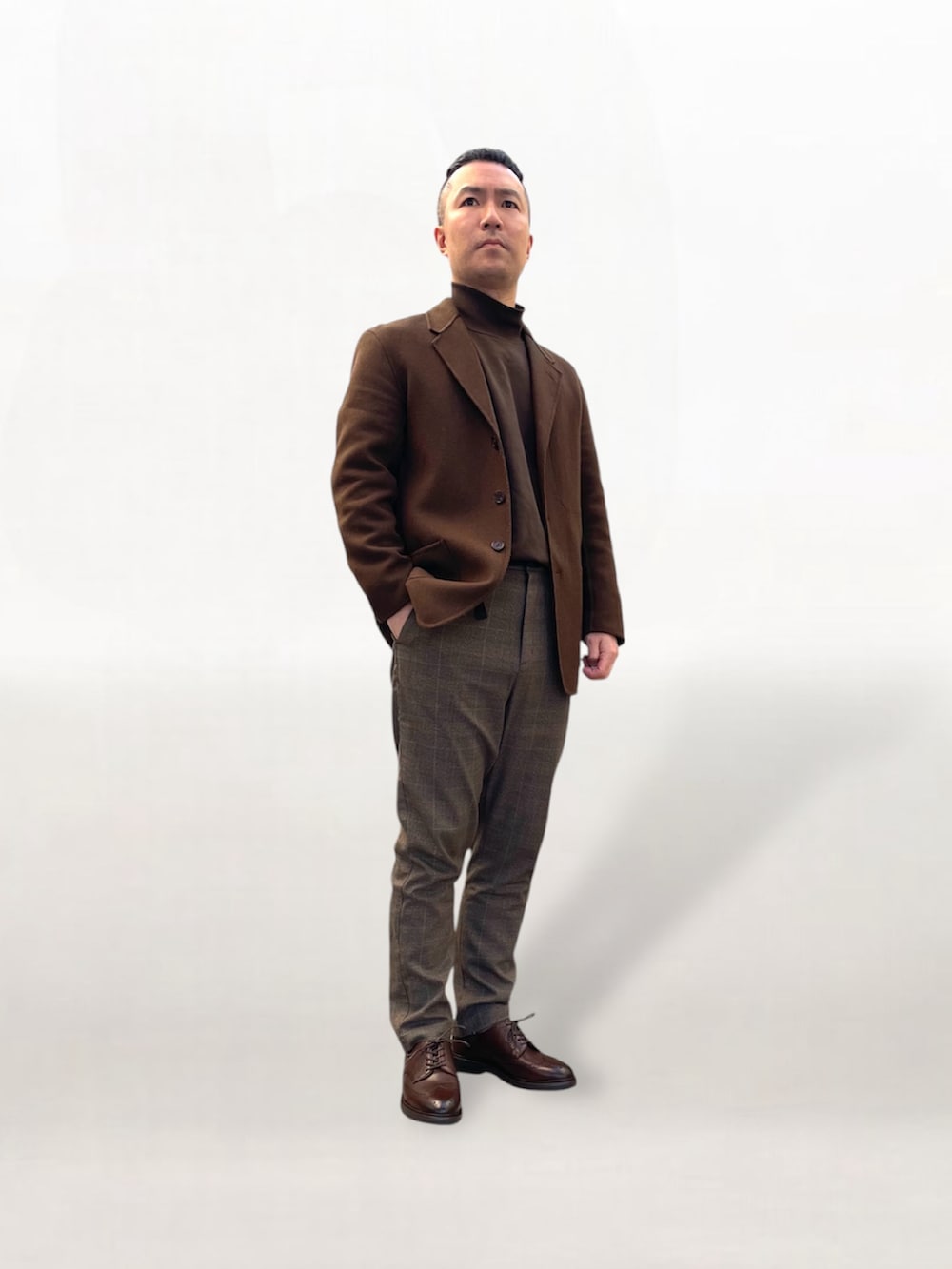 ブラウン系のドレスシューズ、ブラウン系のテーラードジャケット、ブラウン系のスラックスを着用したメンズの冬コーディネートの2枚目の写真