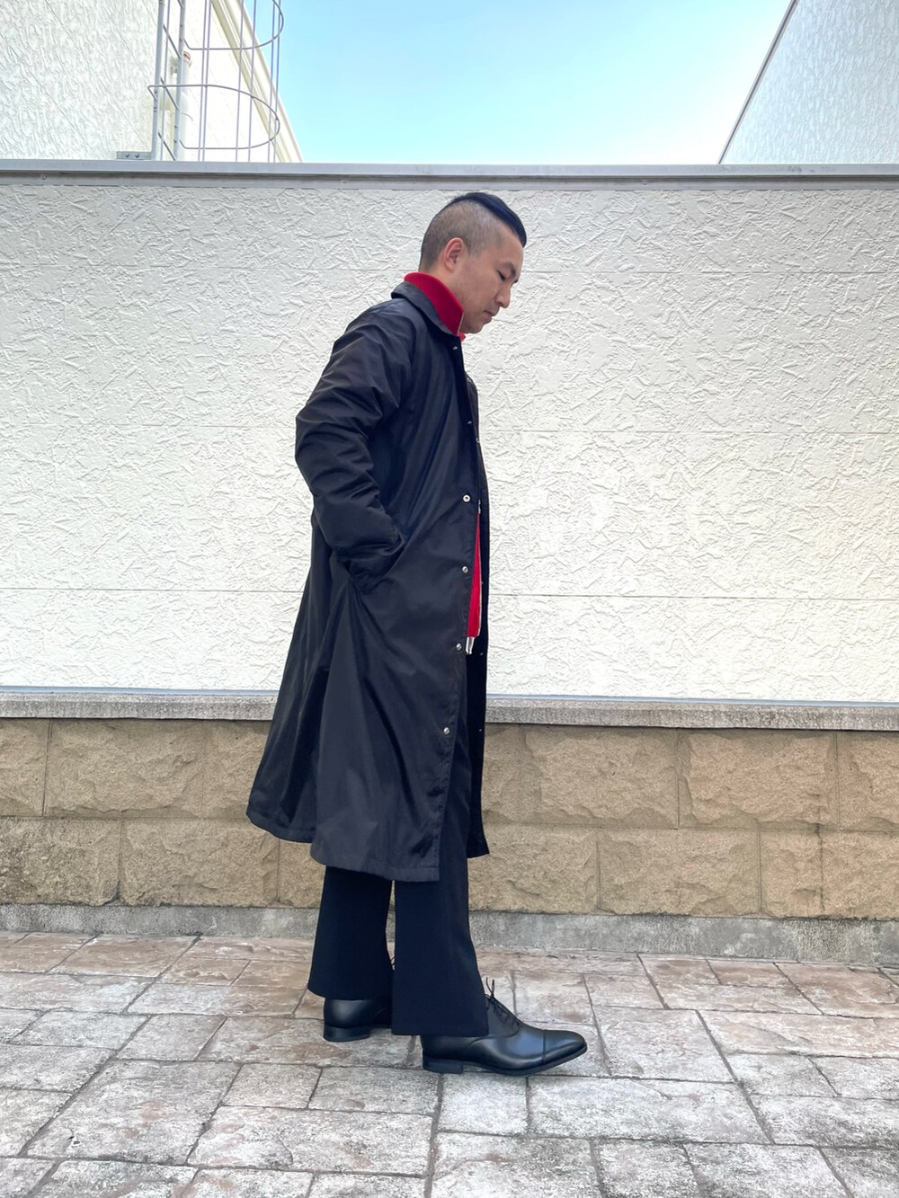 レッド系のニット/セーター、ブラック系のジャケット/アウター、ブラック系のその他パンツを着用したメンズの冬コーディネートの2枚目の写真