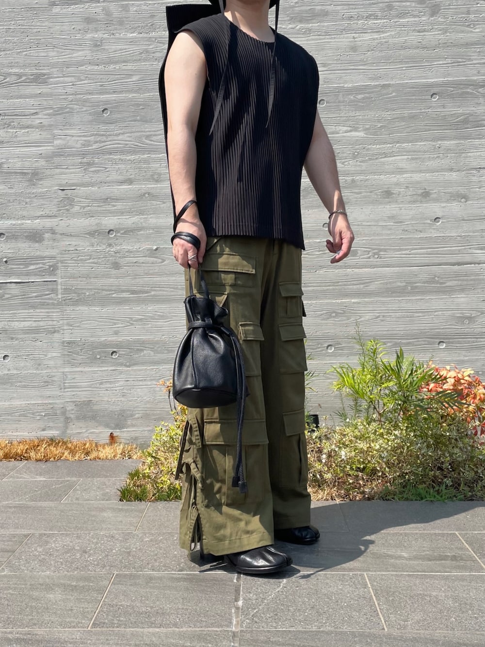 グレー系のベスト、グリーン系のカーゴパンツ、ブラック系のショルダーバッグを着用したメンズの秋コーディネートの4枚目の写真