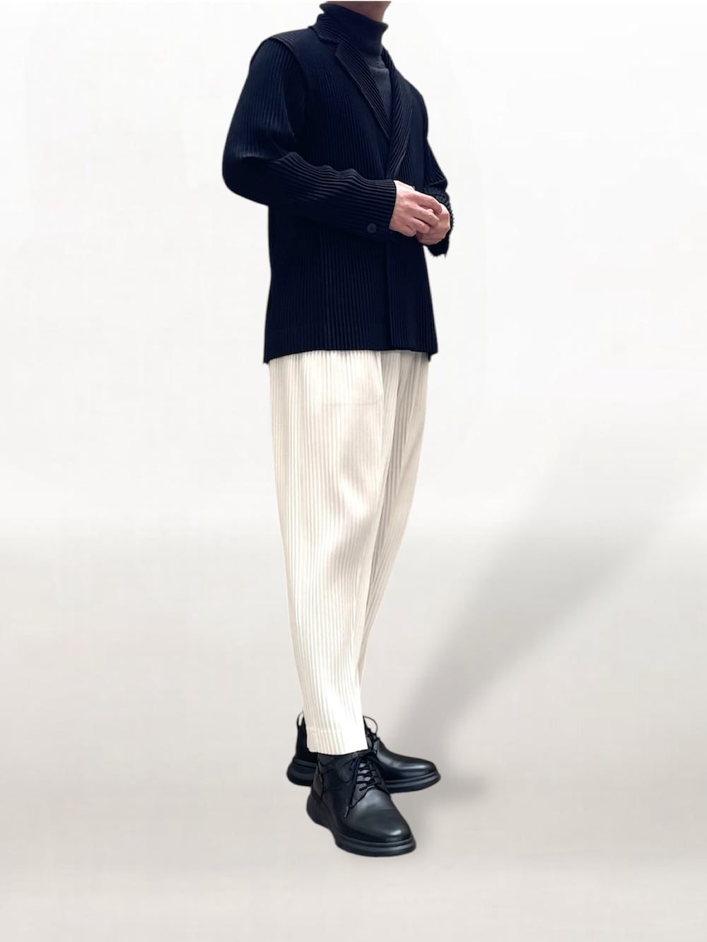 ブラック系のテーラードジャケット、ホワイト系のスラックス、ブラック系のスニーカーを着用したメンズの冬コーディネートの2枚目の写真