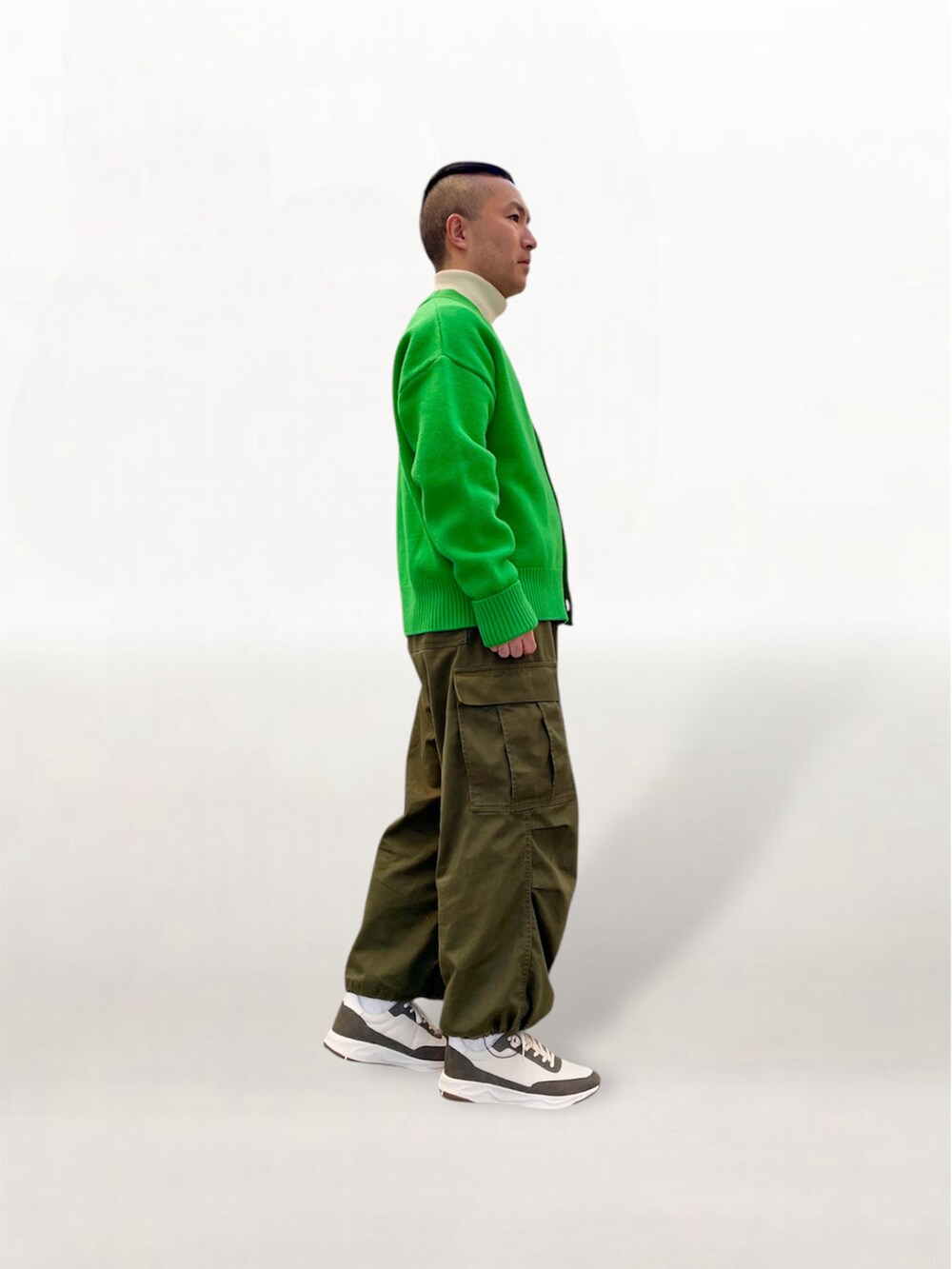 グリーン系のカーディガン/ボレロ、グリーン系のカーゴパンツ、ホワイト系のスニーカーを着用したメンズの冬コーディネートの3枚目の写真