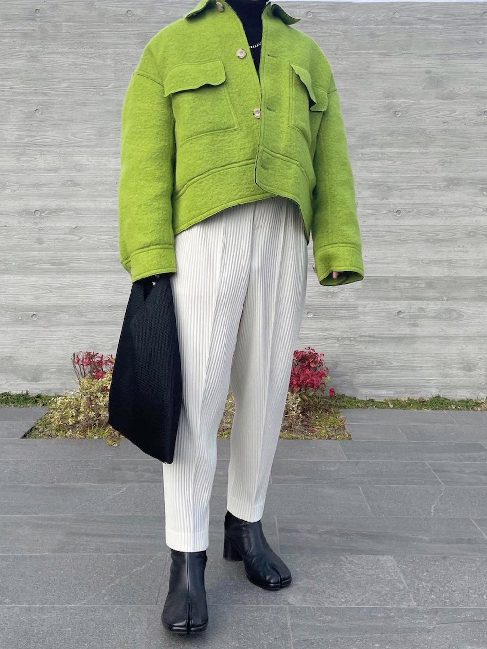 グリーン系のブルゾン、ブラウン系のニット/セーター、ホワイト系のスラックスを着用したメンズの冬コーディネートの2枚目の写真