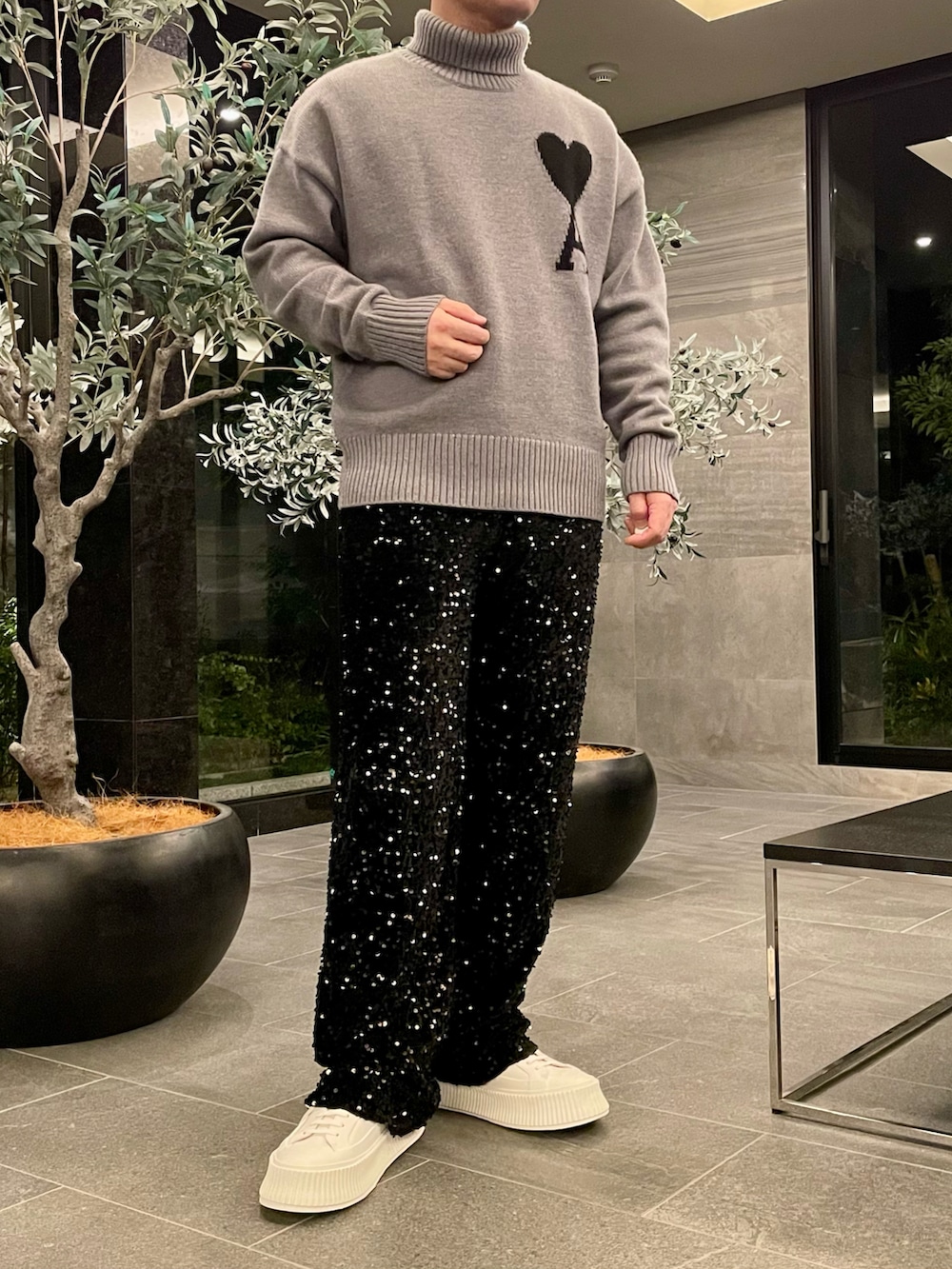 グレー系のニット/セーター、ブラック系のその他パンツ、ホワイト系のスニーカーを着用したメンズの秋コーディネートの3枚目の写真