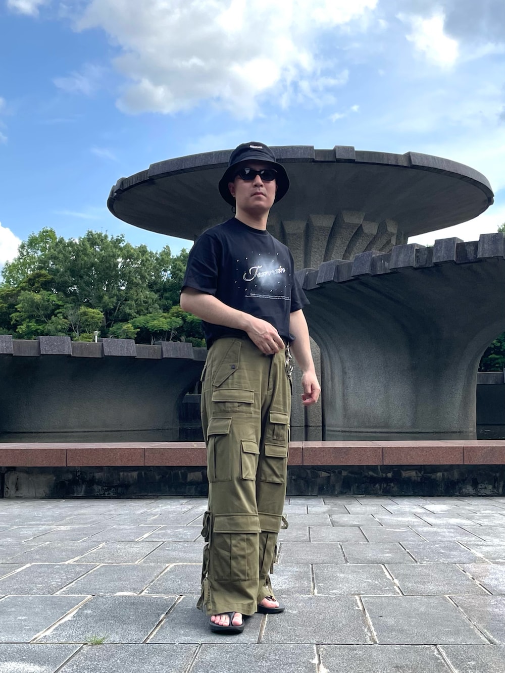 ブラック系のTシャツ/カットソー、グリーン系のカーゴパンツ、ブラック系のサンダルを着用したメンズの夏コーディネートの2枚目の写真