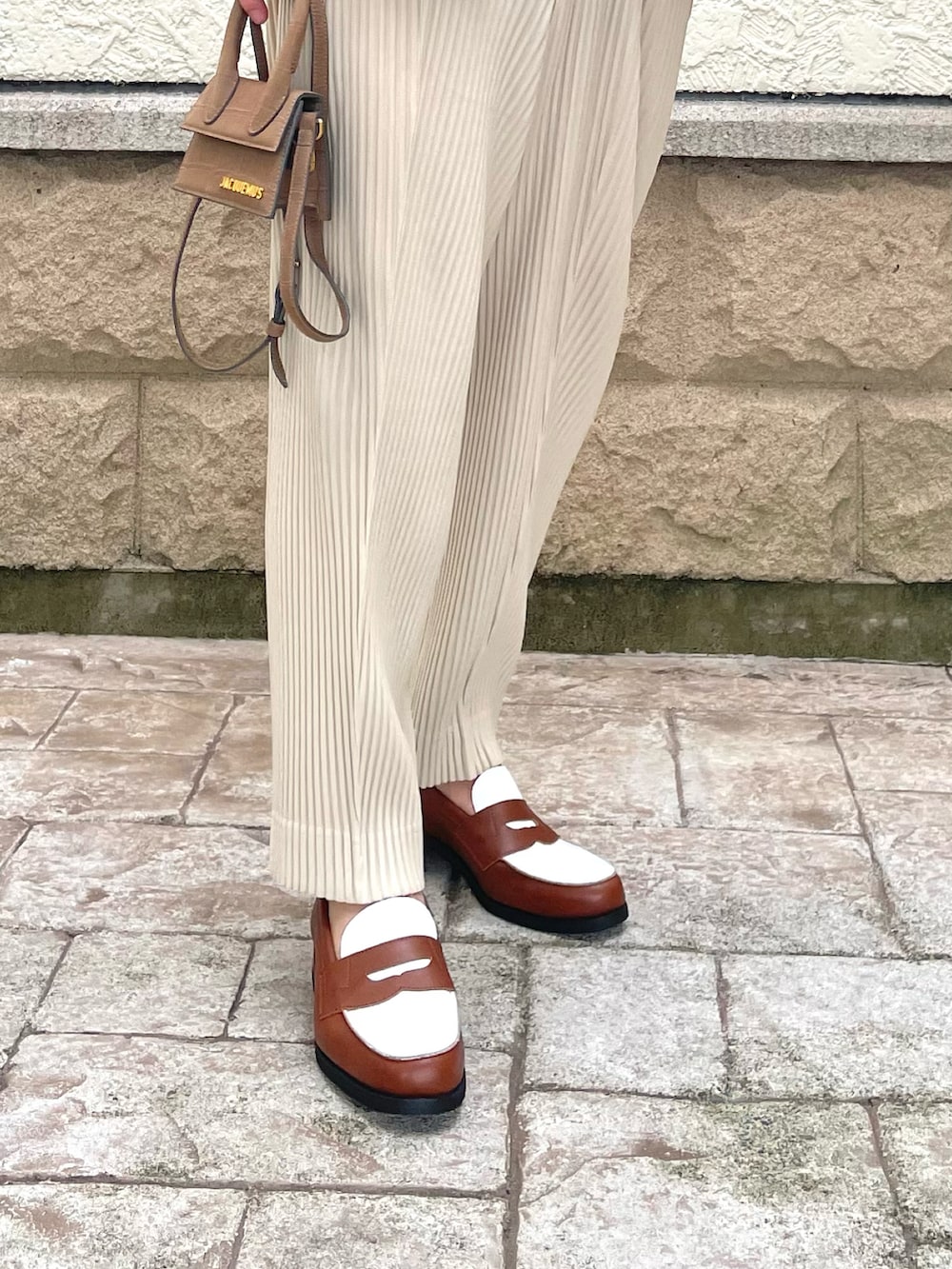 ベージュ系のベスト、ベージュ系のスラックス、ブラウン系のバッグを着用したメンズの夏コーディネートの5枚目の写真