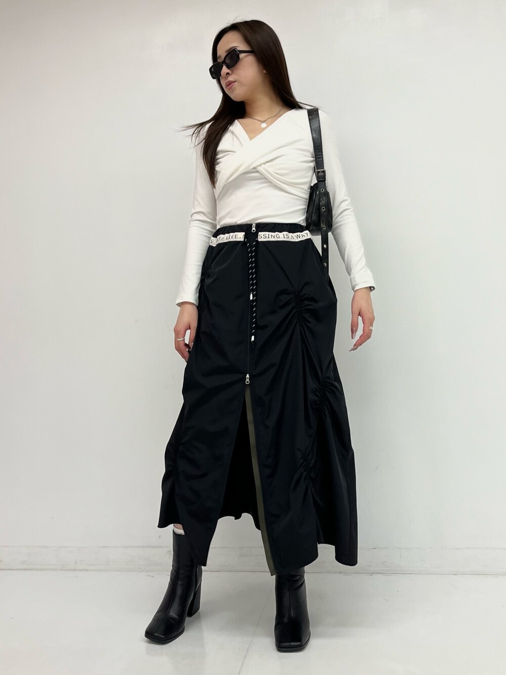 ブラック系のスカート、ホワイト系のTシャツ/カットソーを着用したレディースの春コーディネートの2枚目の写真