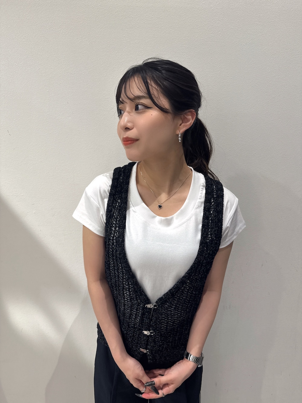 ブラック系のベスト、ホワイト系のTシャツ/カットソー、ブルー系のスラックスを着用したレディースの夏コーディネートの2枚目の写真