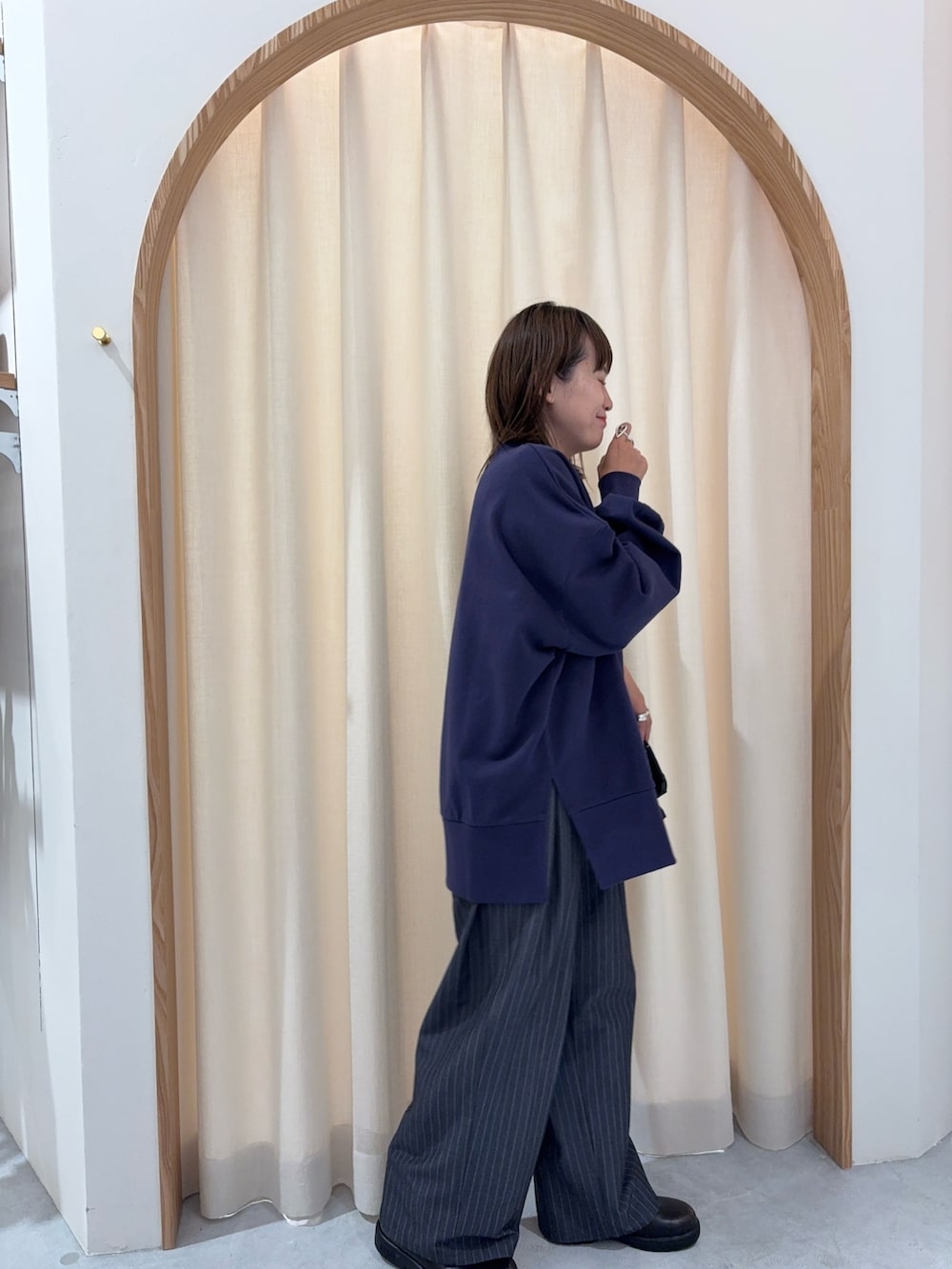 ブルー系のスウェット、グレー系のスラックス、ブラック系のトートバッグを着用したレディースの秋コーディネートの2枚目の写真