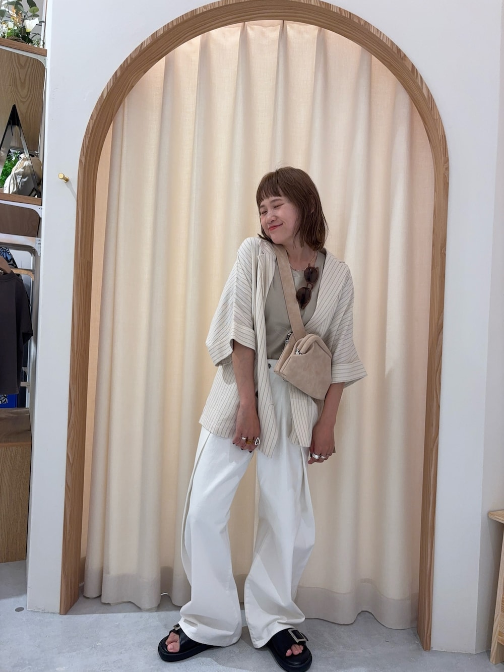 ホワイト系のデニムパンツ、ベージュ系のニット/セーター、ブラック系のサンダルを着用したレディースの夏コーディネートの3枚目の写真