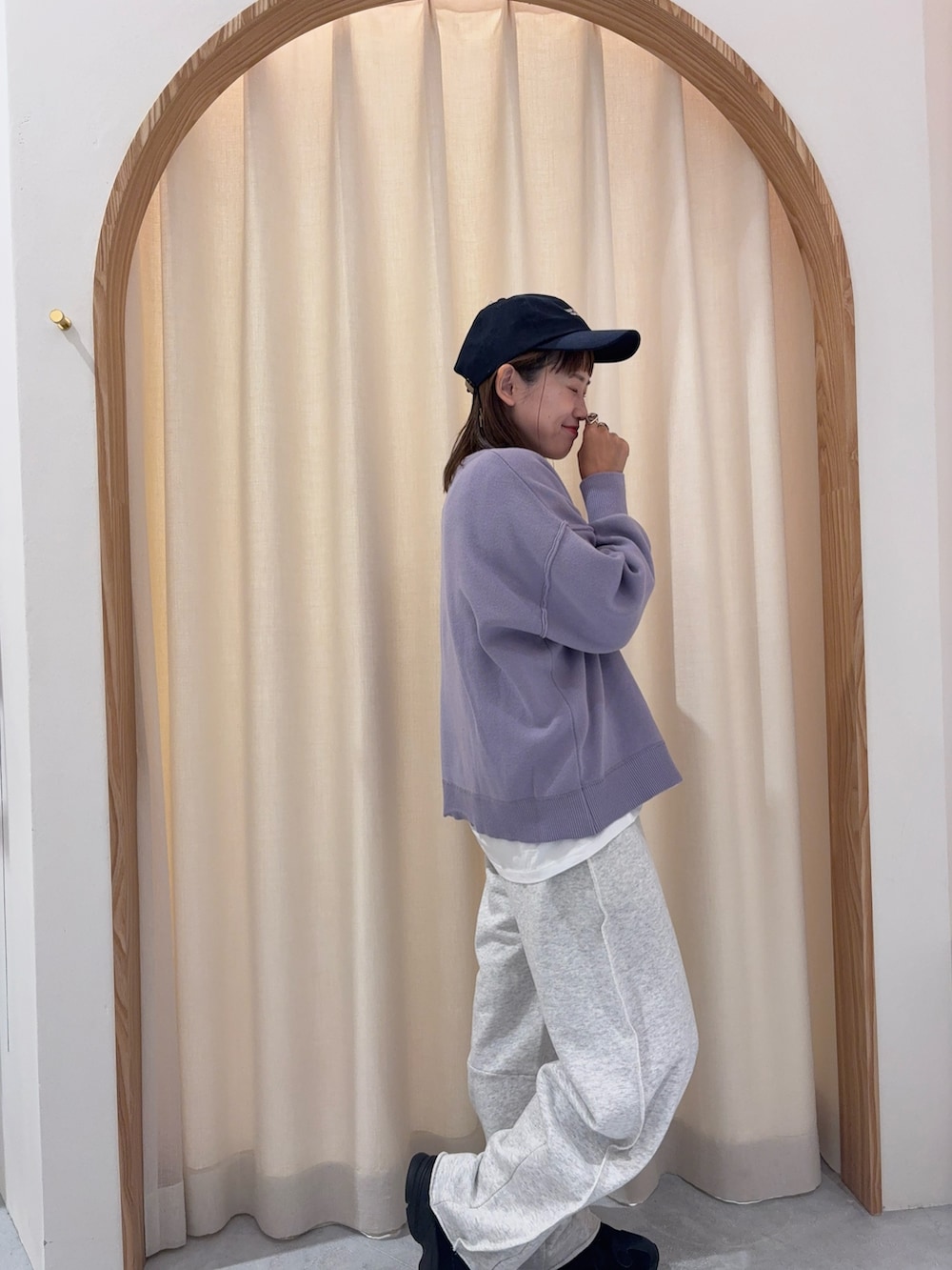 パープル系のニット/セーター、ホワイト系のスウェットパンツ、ブルー系のキャップを着用したレディースの秋コーディネートの3枚目の写真