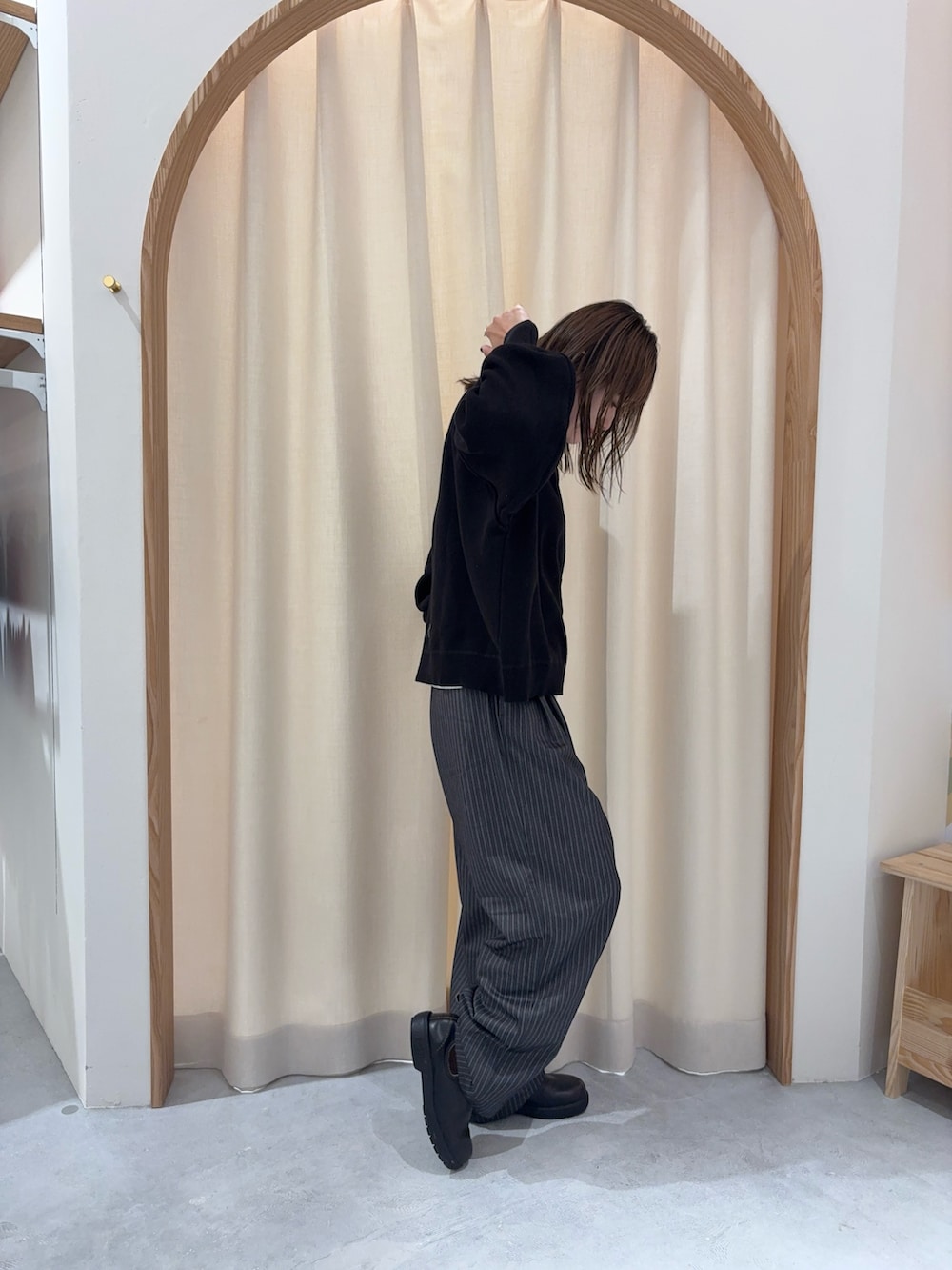 ブラック系のニット/セーター、グレー系のスラックスを着用したレディースの冬コーディネートの3枚目の写真