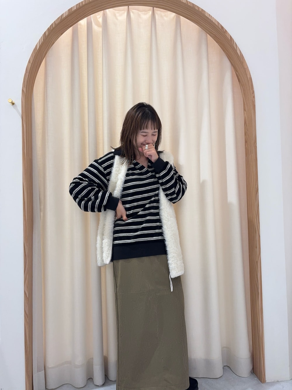 ブラック系のTシャツ/カットソー、ホワイト系のニット/セーター、グリーン系のスカートを着用したレディースの秋コーディネートの3枚目の写真