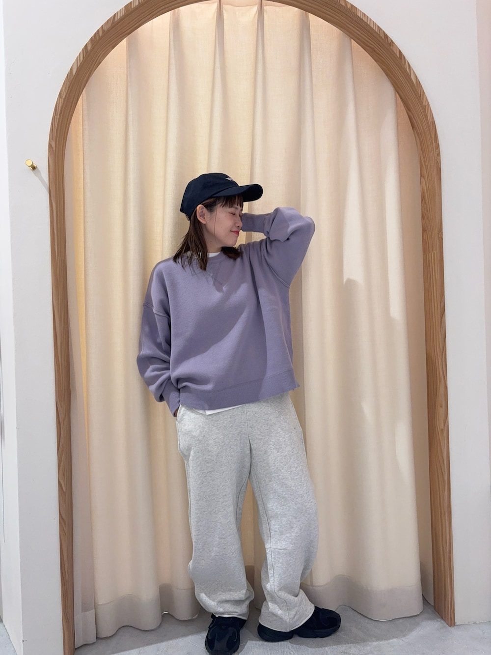 パープル系のニット/セーター、ホワイト系のスウェットパンツ、ブルー系のキャップを着用したレディースの秋コーディネートの2枚目の写真