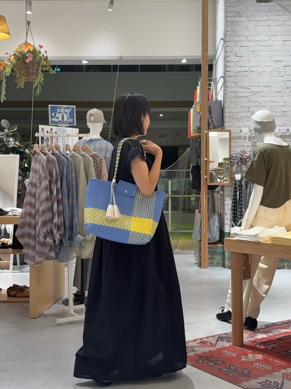 ブラック系のワンピース、イエロー系のサンダル、ブルー系のトートバッグを着用したレディースの夏コーディネートの3枚目の写真