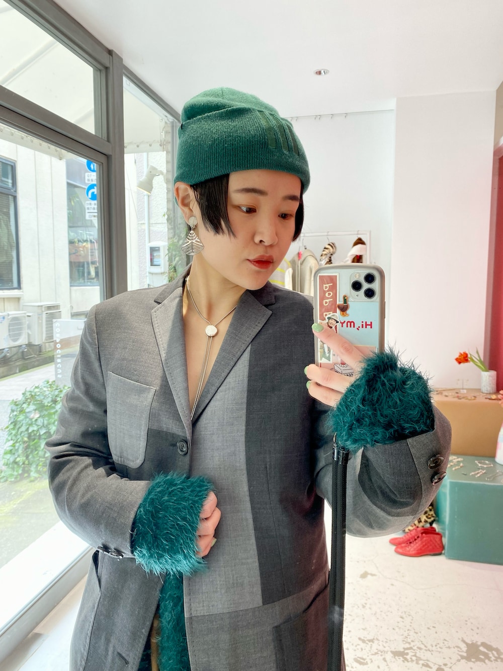 グレー系のジャケット/アウター、グリーン系のカーディガン/ボレロ、ブラウン系のパンツを着用したレディースの春コーディネートの2枚目の写真