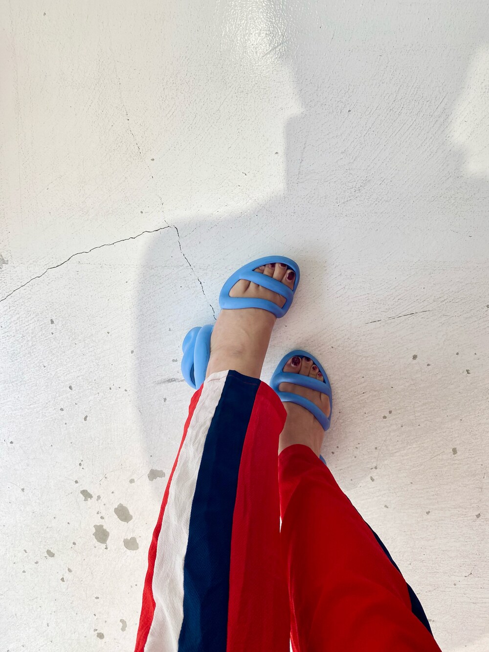 レッド系のオールインワン・サロペット、ブルー系のタンクトップ、ブルー系のサンダルを着用したレディースの夏コーディネートの3枚目の写真