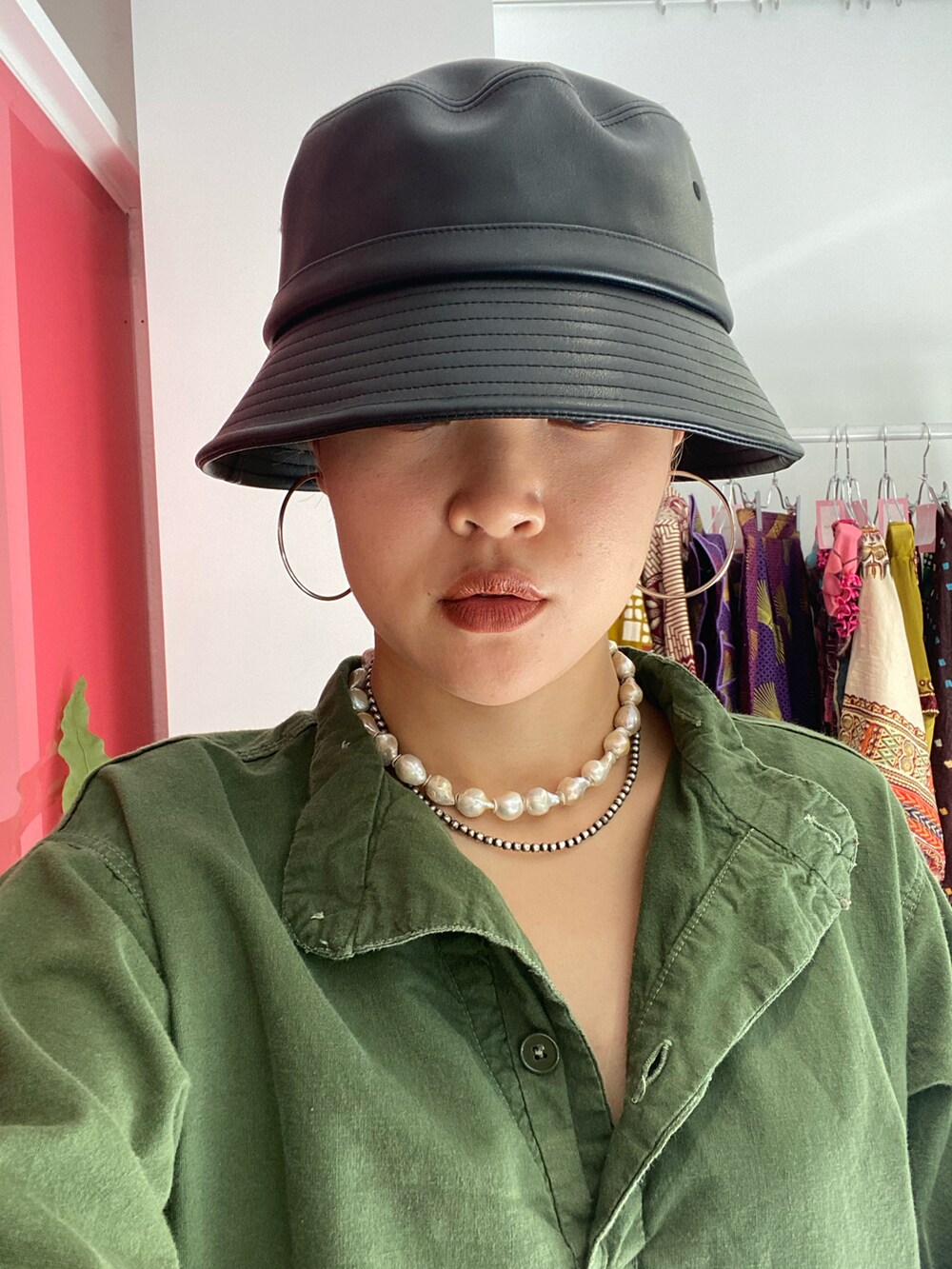 グリーン系のシャツ/ブラウス、ブラック系のハット、ホワイト系のネックレスを着用したレディースの夏コーディネートの2枚目の写真