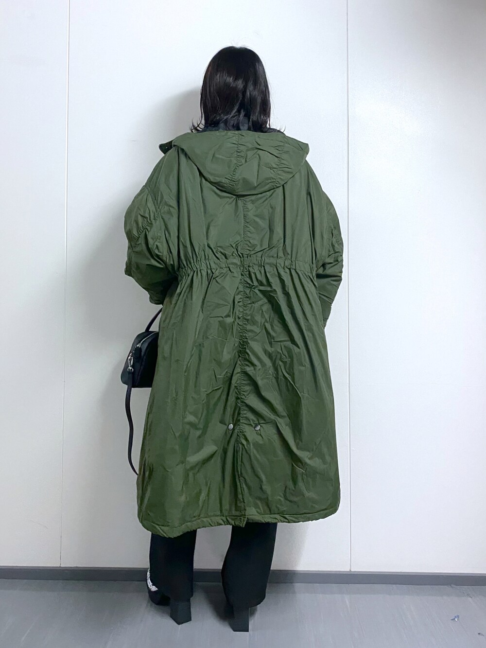 グリーン系のモッズコート、オレンジ系のニット/セーター、ブラック系のボストンバッグを着用したレディースの冬コーディネートの2枚目の写真