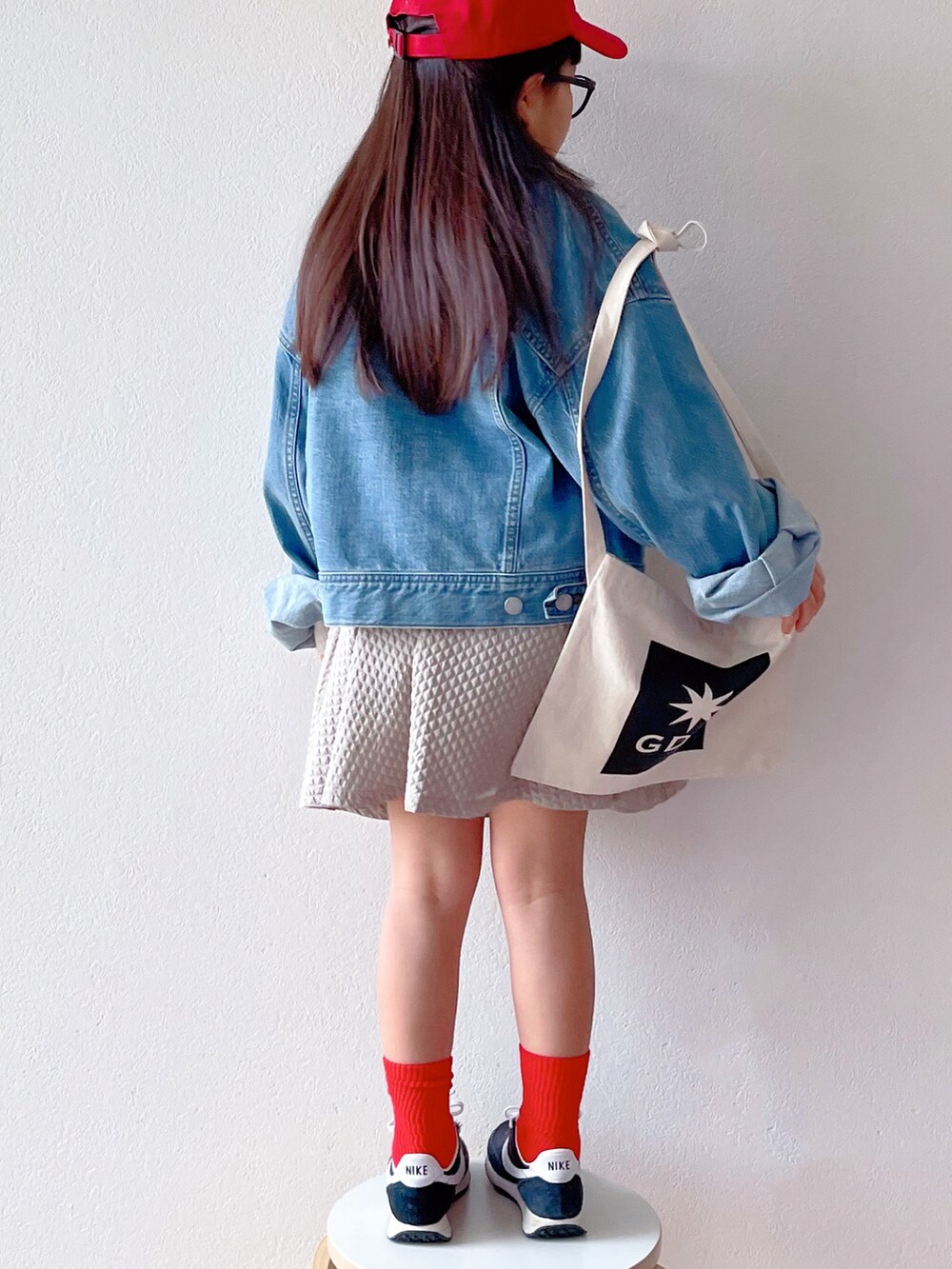 ブルー系のデニムジャケット、ホワイト系のニット/セーター、ベージュ系のスカートを着用したキッズの冬コーディネートの3枚目の写真