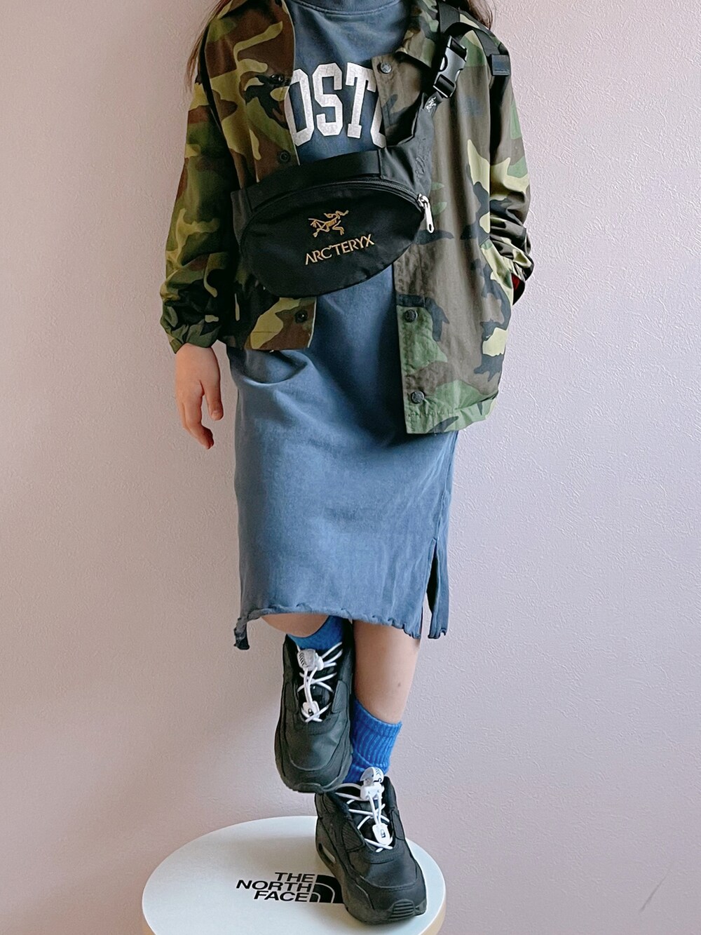 グリーン系のナイロンジャケット、ブルー系のワンピース、ブラック系のボディバッグ/ウエストポーチを着用したキッズの春コーディネートの2枚目の写真