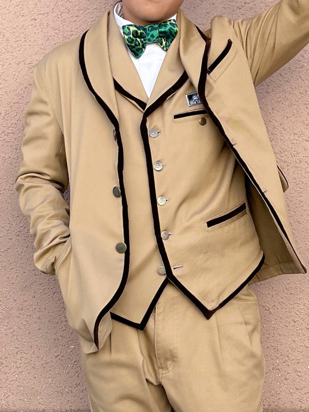 グリーン系の蝶ネクタイ、ベージュ系のスーツセット、ホワイト系のシャツ/ブラウスを着用したキッズの春コーディネートの2枚目の写真