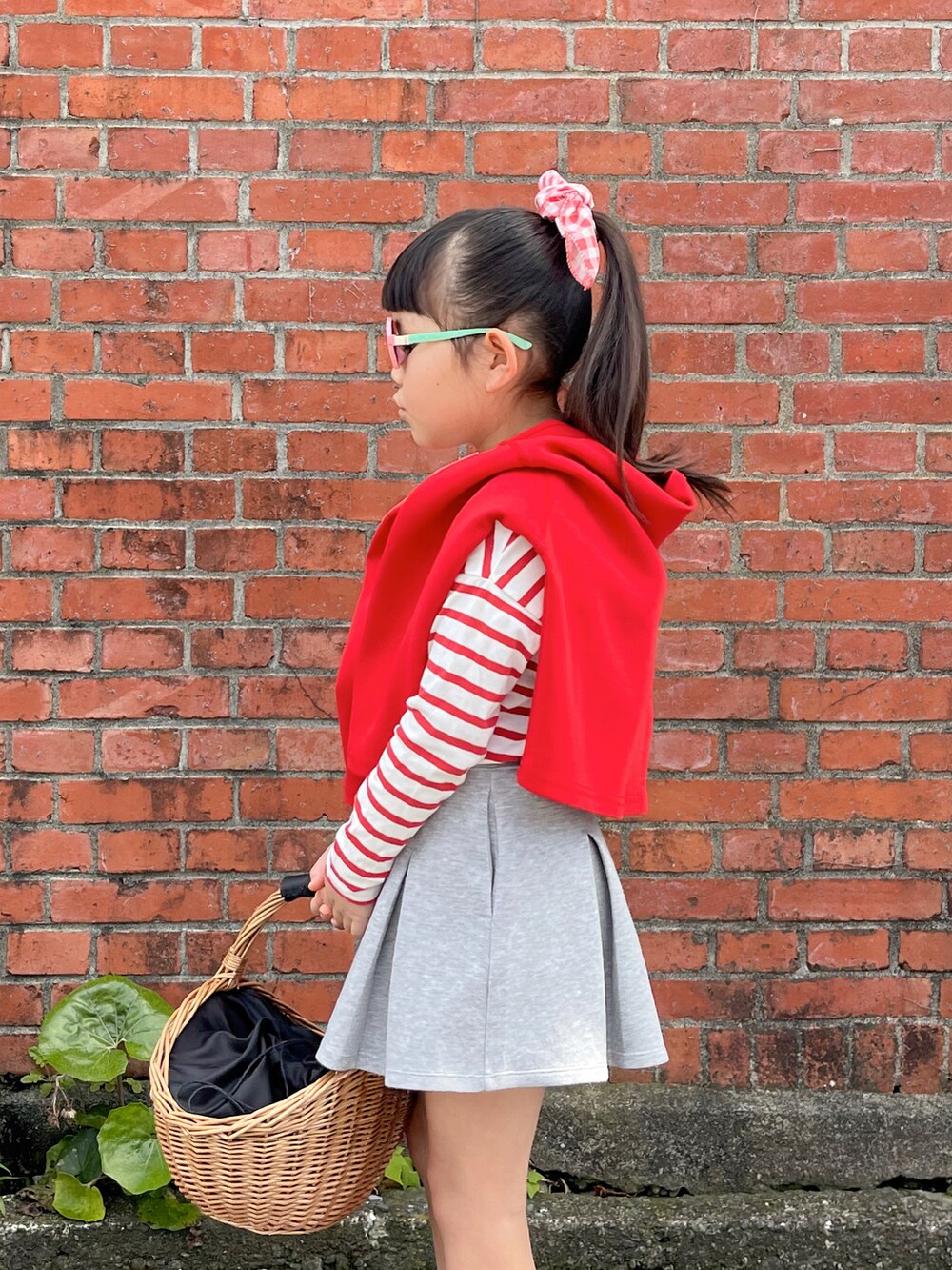 レッド系のTシャツ/カットソー、レッド系のカーディガン/ボレロ、グレー系のスカートを着用したキッズの春コーディネートの2枚目の写真