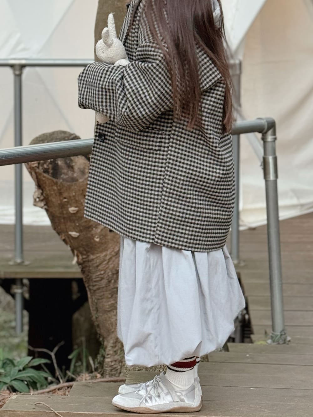 ブルー系のデニムジャケット、レッド系のトートバッグ、ブラック系のチェスターコートを着用したキッズの冬コーディネートの3枚目の写真