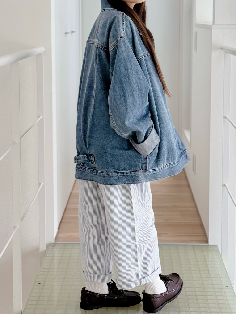 ブルー系のデニムジャケット、ブルー系のサロペット/オーバーオール、ブラウン系のモカシン/デッキシューズを着用したキッズの春コーディネートの2枚目の写真