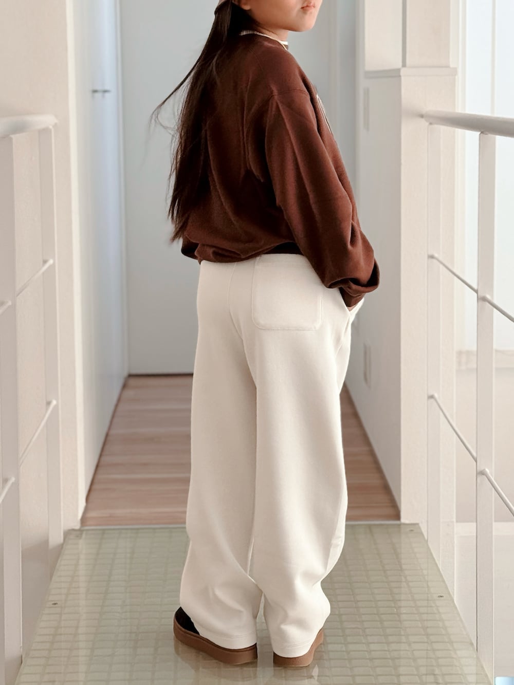 ブラウン系のスウェット、ホワイト系のスウェットパンツ、ブラック系のスニーカーを着用したキッズの秋コーディネートの2枚目の写真