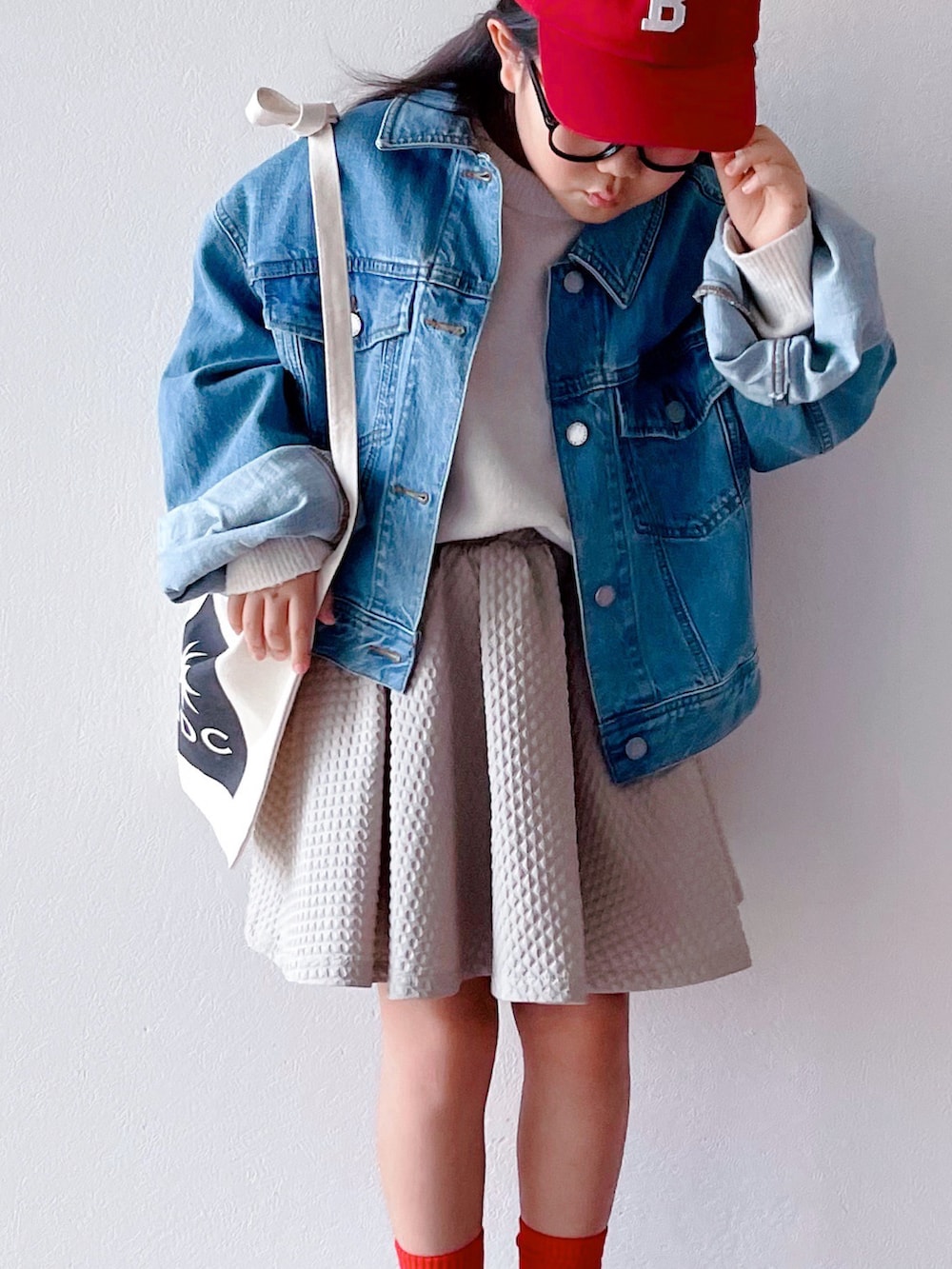 ブルー系のデニムジャケット、ホワイト系のニット/セーター、ベージュ系のスカートを着用したキッズの冬コーディネートの2枚目の写真