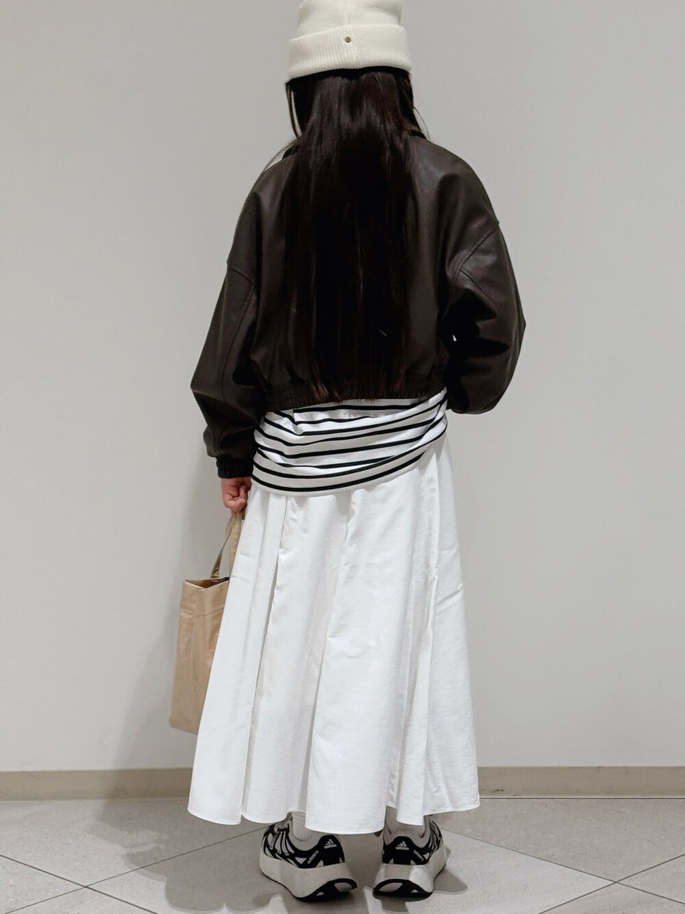 ホワイト系のスニーカー、ベージュ系のトートバッグ、ブラウン系のブルゾンを着用したキッズの春コーディネートの3枚目の写真