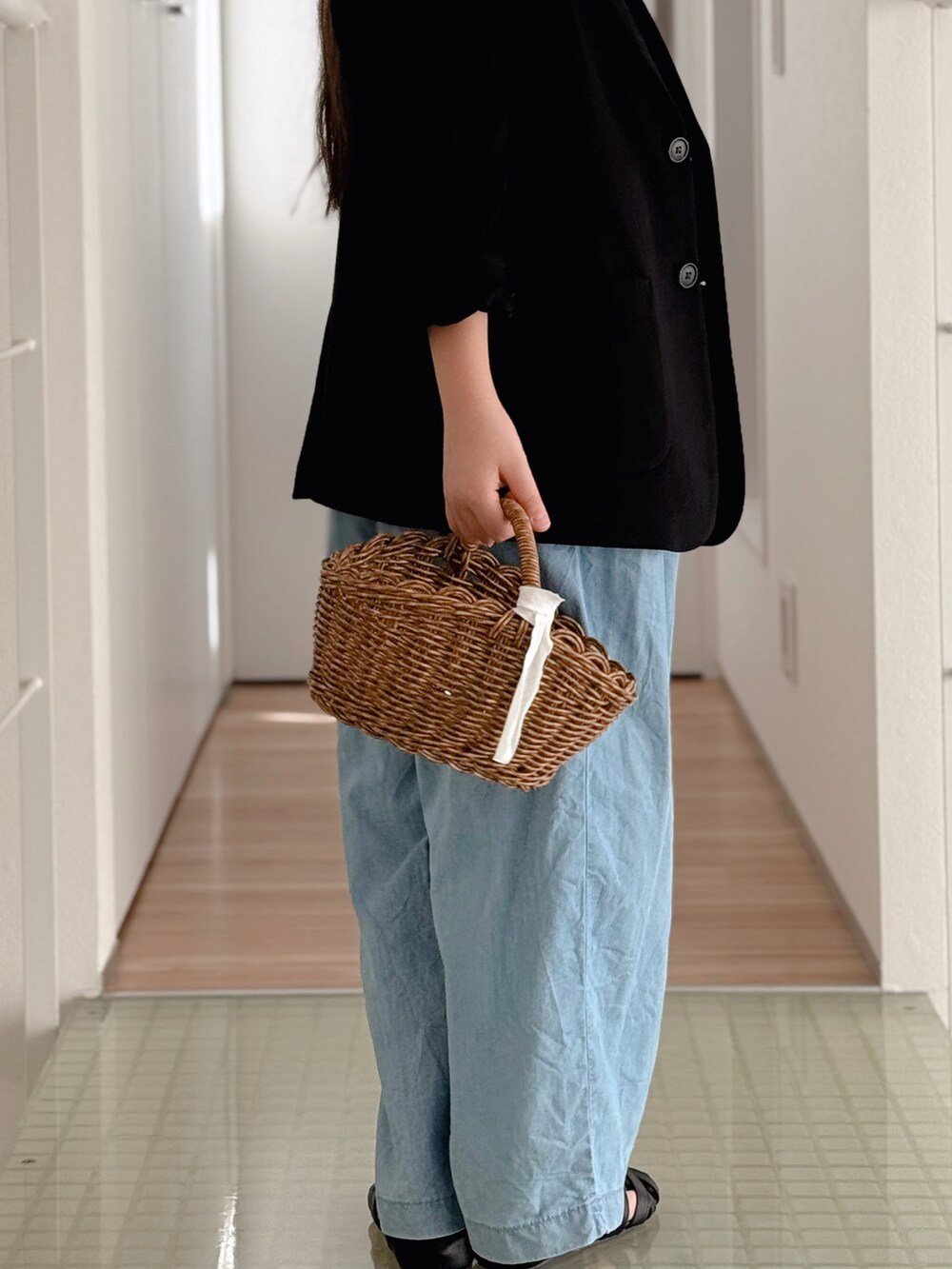 ブルー系のデニムパンツ、ベージュ系のかごバッグ、ブラック系のサンダルを着用したキッズの春コーディネートの3枚目の写真