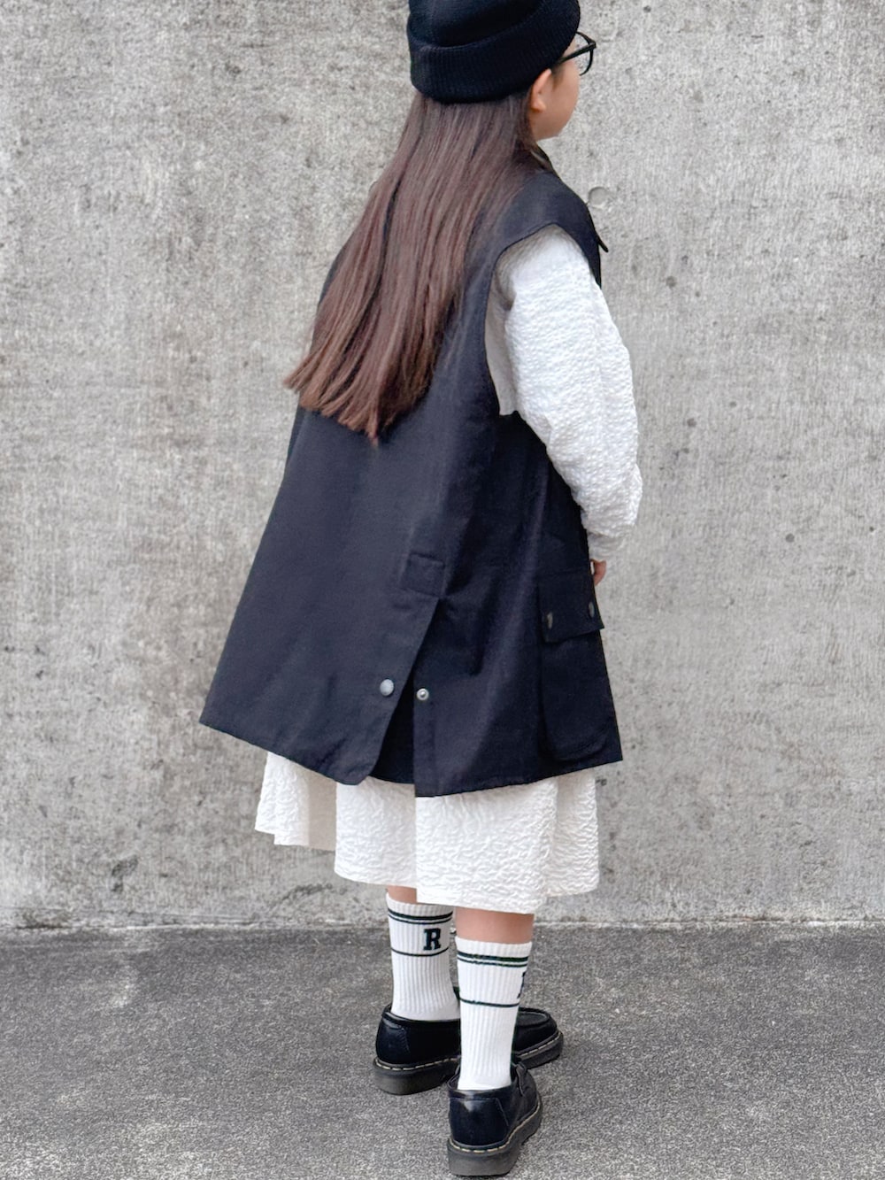 ブラック系のテーラードジャケット、ホワイト系のシャツ/ブラウス、ホワイト系のスカートを着用したキッズの冬コーディネートの2枚目の写真