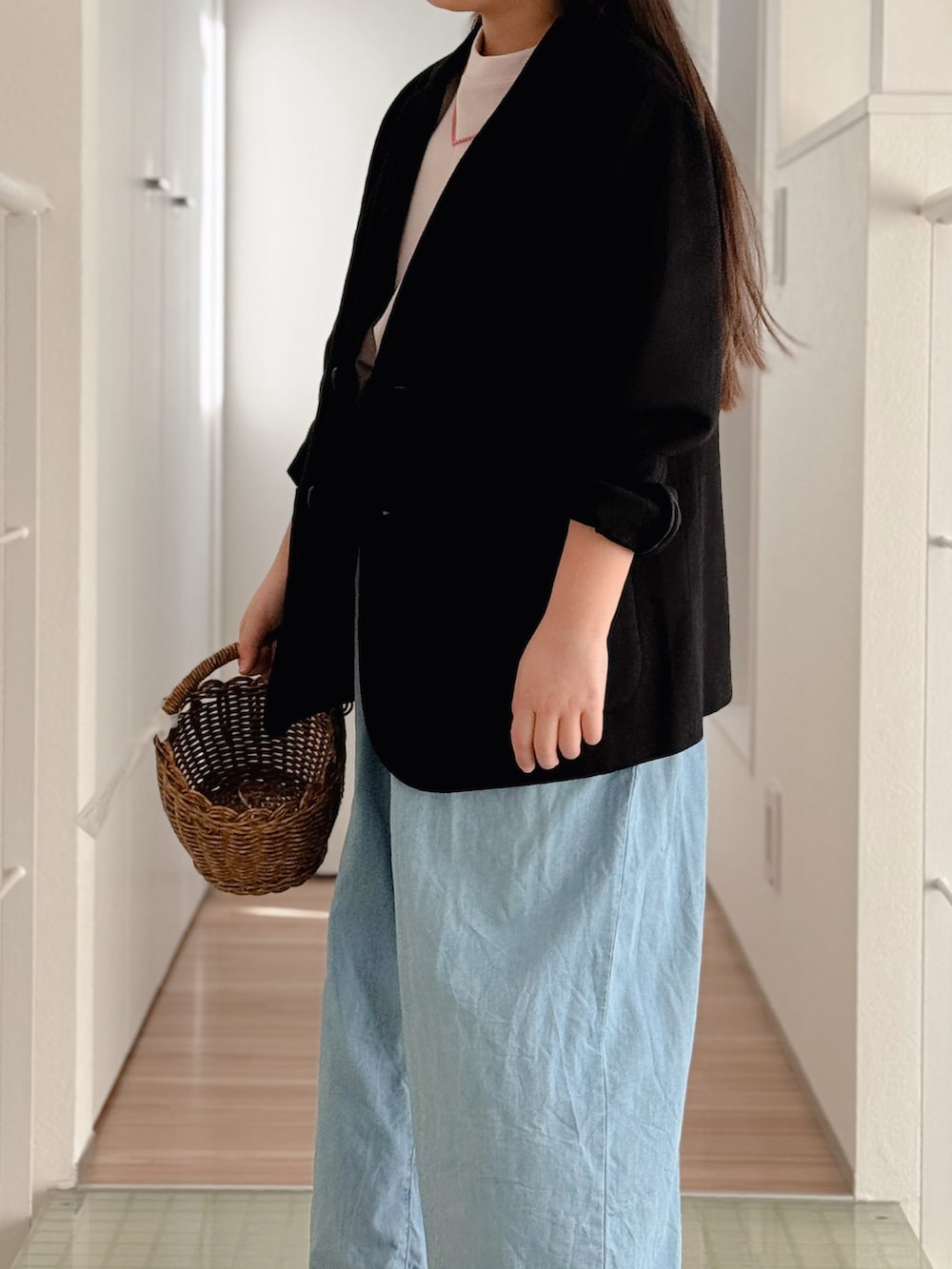 ブルー系のデニムパンツ、ベージュ系のかごバッグ、ブラック系のサンダルを着用したキッズの春コーディネートの2枚目の写真