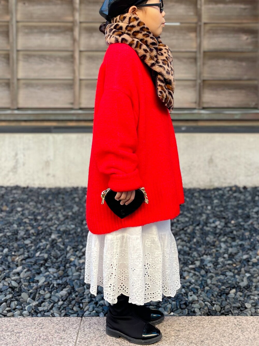 レッド系のニット/セーター、ホワイト系のスカート、ブラック系のブーツを着用したキッズの冬コーディネートの2枚目の写真