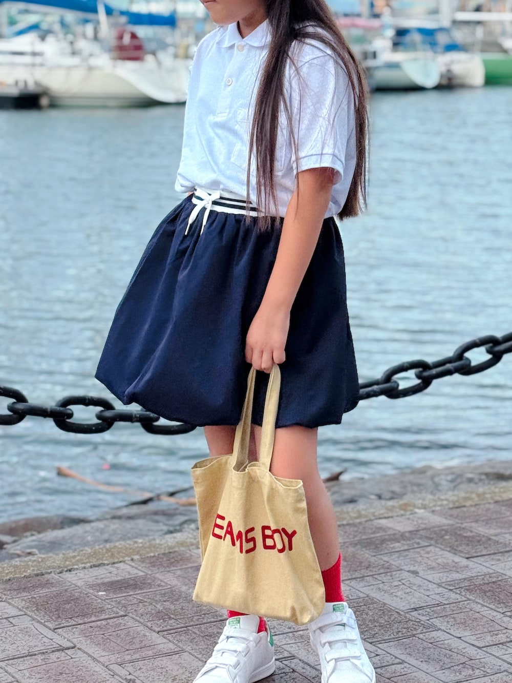 ホワイト系のスニーカー、ホワイト系のポロシャツ、ブルー系のスカートを着用したキッズの夏コーディネートの3枚目の写真